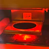 Red-lit scientific or industrial machine with warning symbol