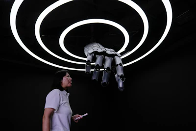 A staff walks in front of robotic arm at the Robot Mall, World's first embodied intelligent robot 4S store in Beijing, China, Wednesday, Aug. 6, 2025.