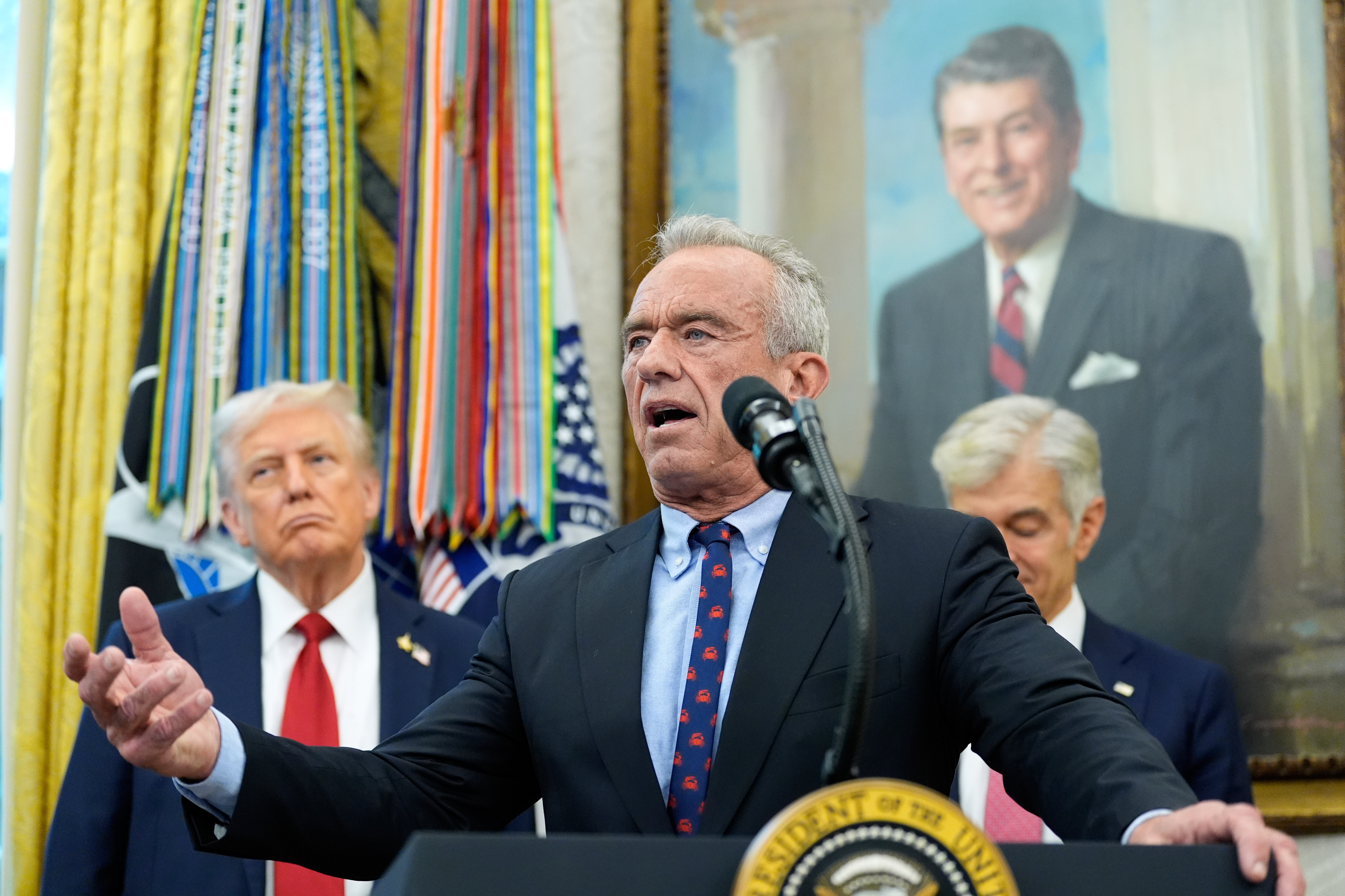 Secretary of Health and Human Services Robert F. Kennedy, Jr., speaks in the Oval Office of the White House, Tuesday, Sept. 30, 2025, in Washington, as President Donald Trump, left, and Mehmet Oz, Administrator for the Centers for Medicare & Medicaid Services, look on.