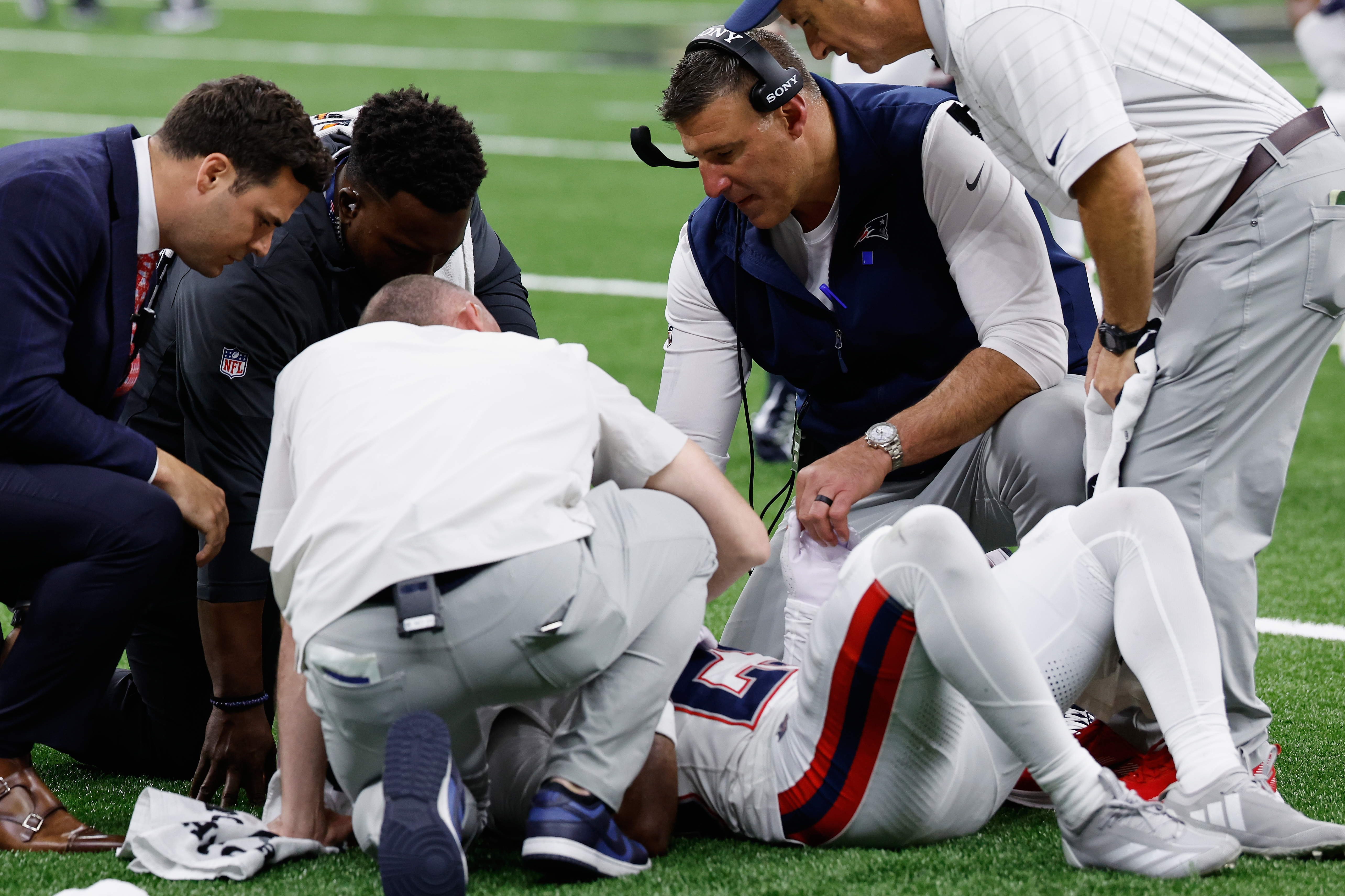 New England Patriots head coach Mike Vrabel, second from right, checks on cornerback Marcus Jones after an injury during the second half of an NFL football game against the New Orleans Saints, Sunday, Oct. 12, 2025, in New Orleans.