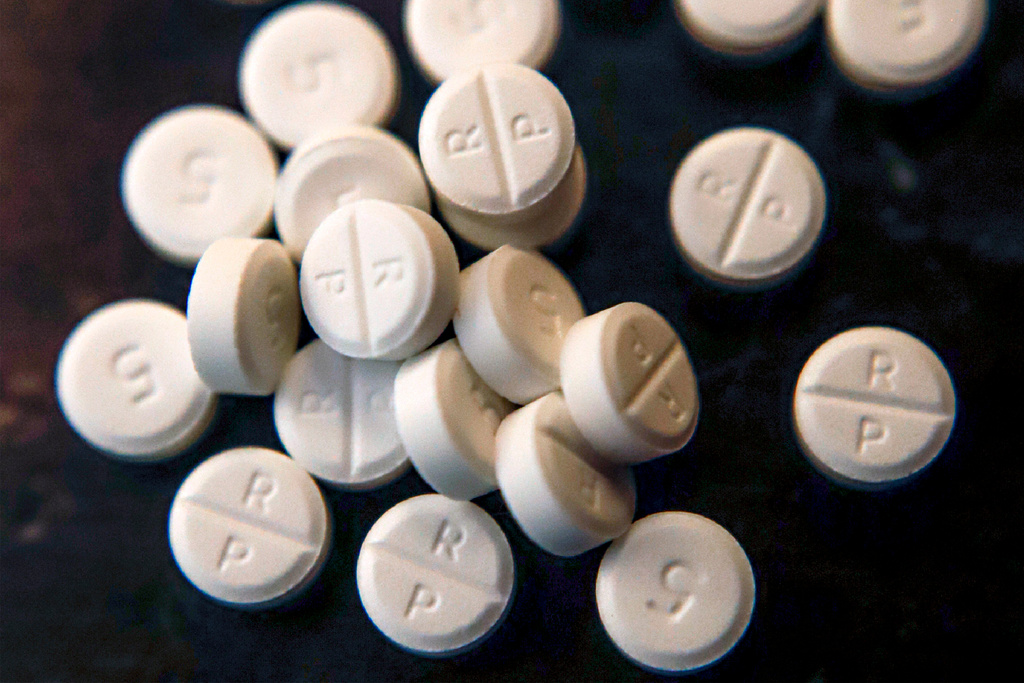 White pharmaceutical tablets scattered on dark background