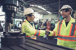 Factory workers shake hands in the factory.
