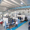 Industrial manufacturing facility with CNC machines and workers on blue-lined floor