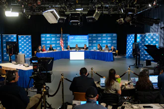 EAC government panel discussion with officials seated at blue-draped table, cameras and audience in foreground