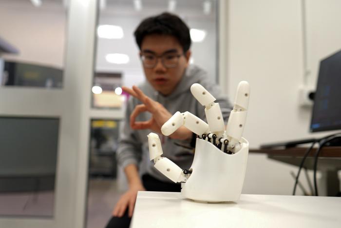 Graduate student Dian Li working with a robotic hand.