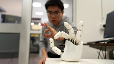 Graduate student Dian Li working with a robotic hand.