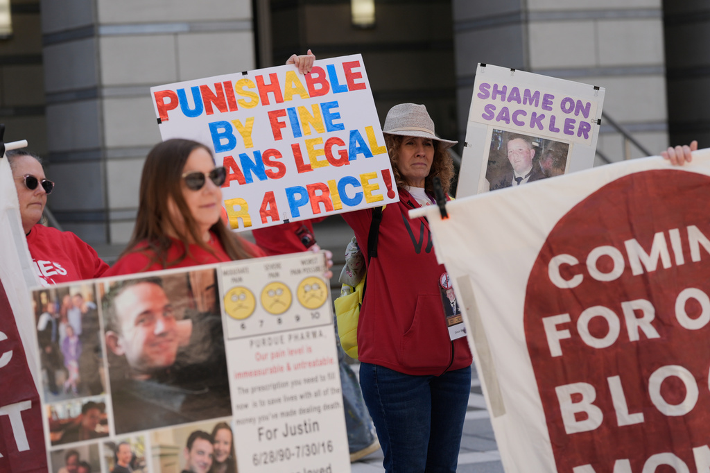 Protesters holding colorful handmade signs advocating for justice and accountability at a public demonstration.