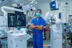 Joseph Osorio, MD, PhD, neurosurgeon at San Diego Health, stands beside the new AI-powered robotic spine surgery system in an operating room at Jacobs Medical Center.