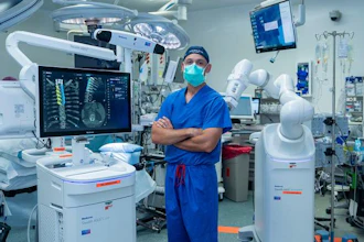 Joseph Osorio, MD, PhD, neurosurgeon at San Diego Health, stands beside the new AI-powered robotic spine surgery system in an operating room at Jacobs Medical Center.