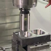 CNC press machine with cylindrical punch tool positioned above metal workpiece with two circular cavities