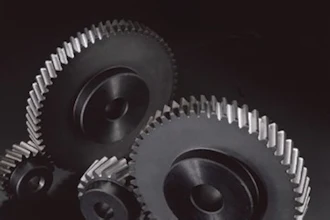 Metallic gears and cogwheels arranged on dark background, representing mechanical engineering and industrial machinery