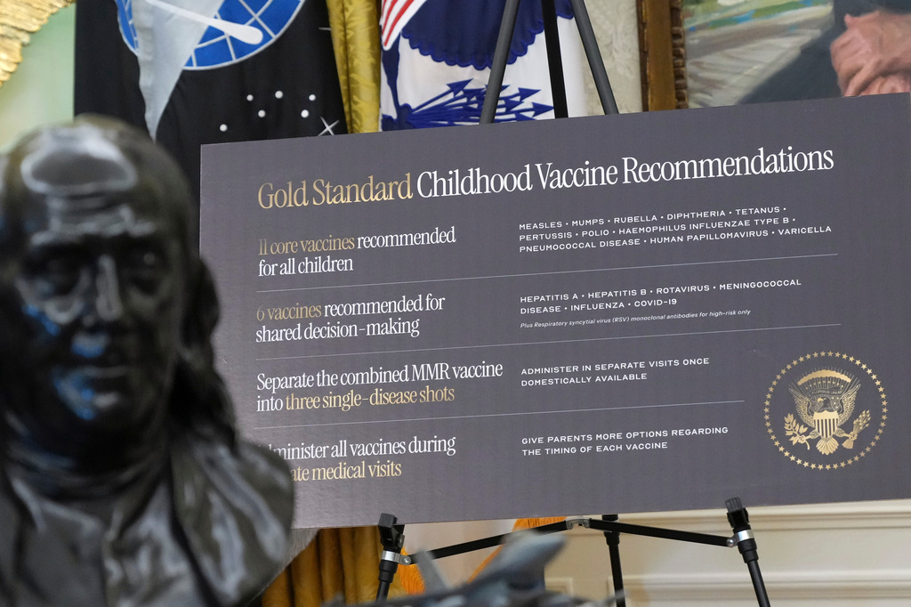 A sign about childhood vaccines is pictured as President Donald Trump speaks during a meeting to sign an executive order, Monday, Aug. 10, 2026, in the Oval Office of the White House in Washington.