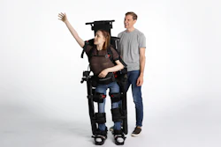 Woman wearing black motorized exoskeleton with man standing beside her against white background