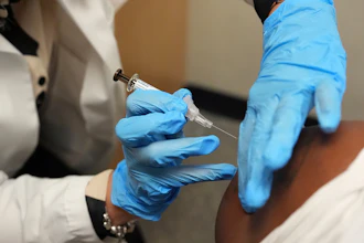 Healthcare professional in blue gloves administering injection to patient's arm during medical procedure