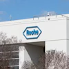 Roche pharmaceutical company logo on white industrial building facade with blue sky