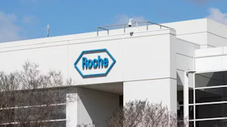 Roche pharmaceutical company logo on white industrial building facade with blue sky