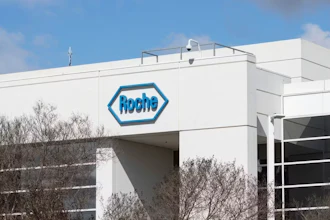 Roche pharmaceutical company logo on white industrial building facade with blue sky