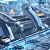 Robotic arms assembling circuit boards in a high-tech manufacturing facility with blue lighting