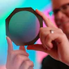 Radiation oncology medical physicist Dr. Michael Grams holds a device called a tungsten collimator that divides a conventional radiation beam into submillimeter-wide beamlets.