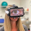 Woman wearing VR headset displaying close-up eye imagery on screen in fitness studio setting