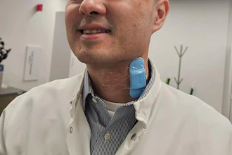 Professional man in white lab coat and striped shirt smiling in modern office environment