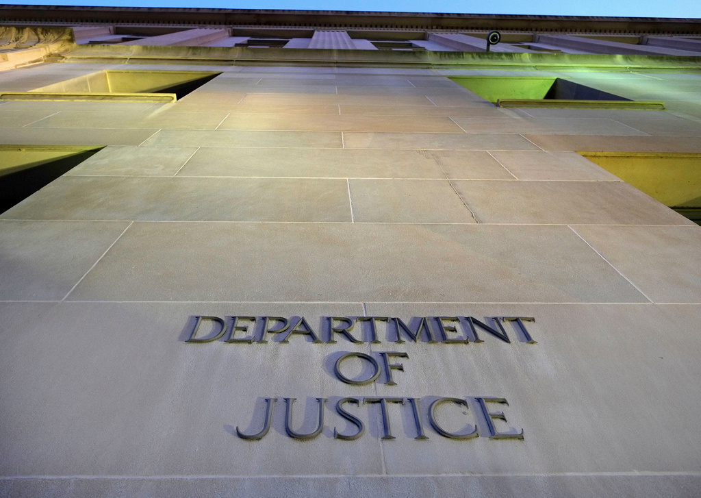 Department of Justice engraved lettering on stone building exterior with green-lit architectural features