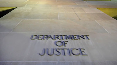 Department of Justice engraved lettering on stone building exterior with green-lit architectural features