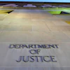 Department of Justice engraved lettering on stone building exterior with green-lit architectural features
