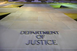 Department of Justice engraved lettering on stone building exterior with green-lit architectural features