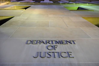 Department of Justice engraved lettering on stone building exterior with green-lit architectural features