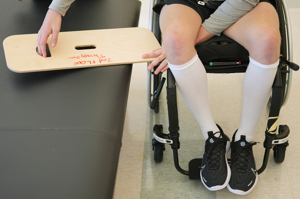 Person in wheelchair holding wooden board with handwritten text during indoor activity