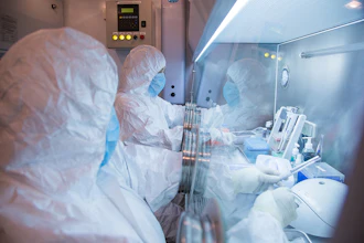 Laboratory technicians in protective suits working in a biosafety cabinet with scientific equipment
