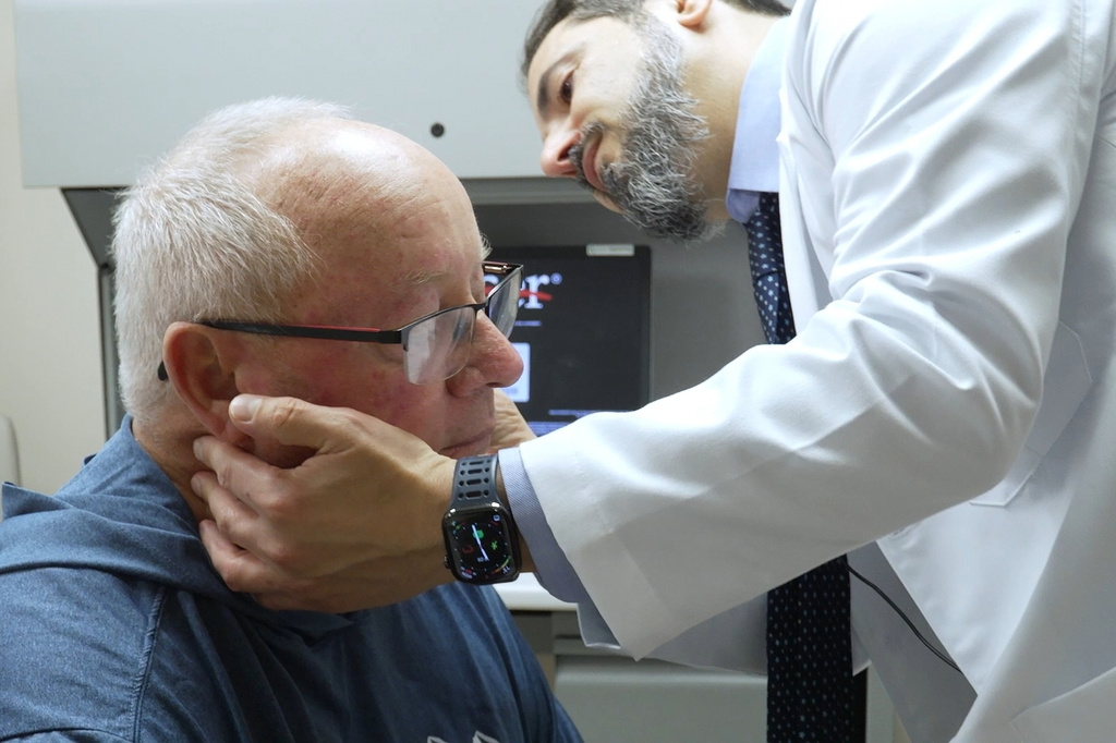 Doctor performing neck examination on elderly patient in clinical setting