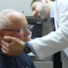 Doctor performing neck examination on elderly patient in clinical setting