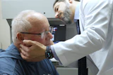 Doctor performing neck examination on elderly patient in clinical setting