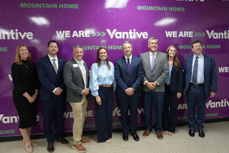 Eight business professionals posing at a Vantive Mountain Home corporate event with purple branded backdrop