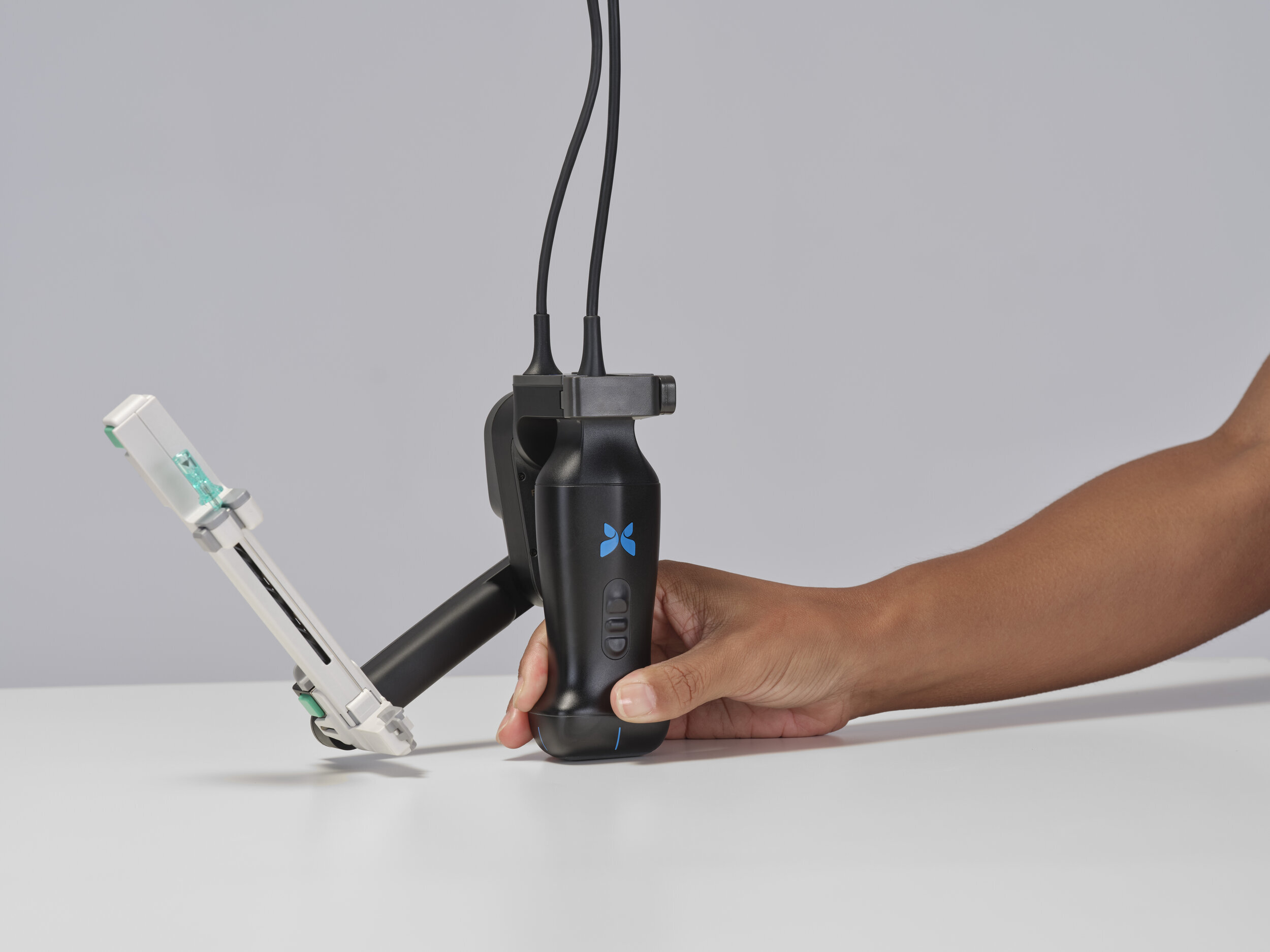 Person holding black handheld gimbal stabilizer with blue X logo and attached smartphone mount