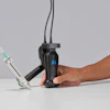 Person holding black handheld gimbal stabilizer with blue X logo and attached smartphone mount