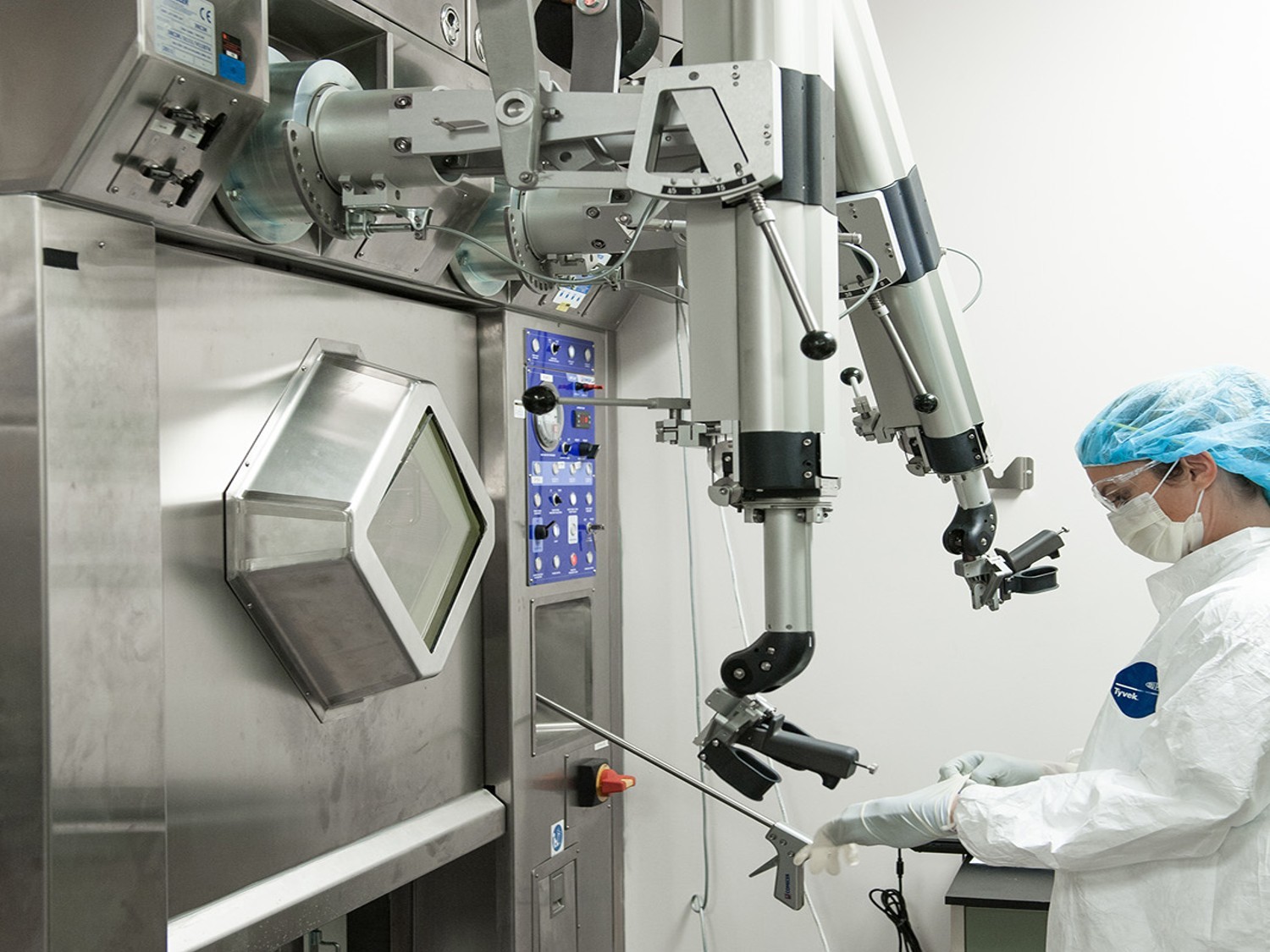 Surgeon in sterile attire operating advanced robotic surgical system with articulated arms and control interface