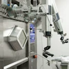 Surgeon in sterile attire operating advanced robotic surgical system with articulated arms and control interface