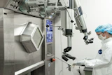 Surgeon in sterile attire operating advanced robotic surgical system with articulated arms and control interface
