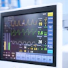 Hospital patient monitor displaying vital signs including heart rate, oxygen saturation, and waveform tracings in clinical setting