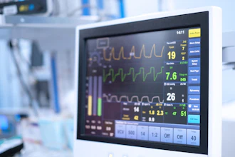 Hospital patient monitor displaying vital signs including heart rate, oxygen saturation, and waveform tracings in clinical setting