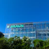 B. Braun corporate headquarters building with green illuminated signage on modern glass facade