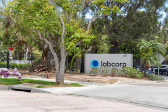 Labcorp corporate sign at building entrance with mature trees and landscaping