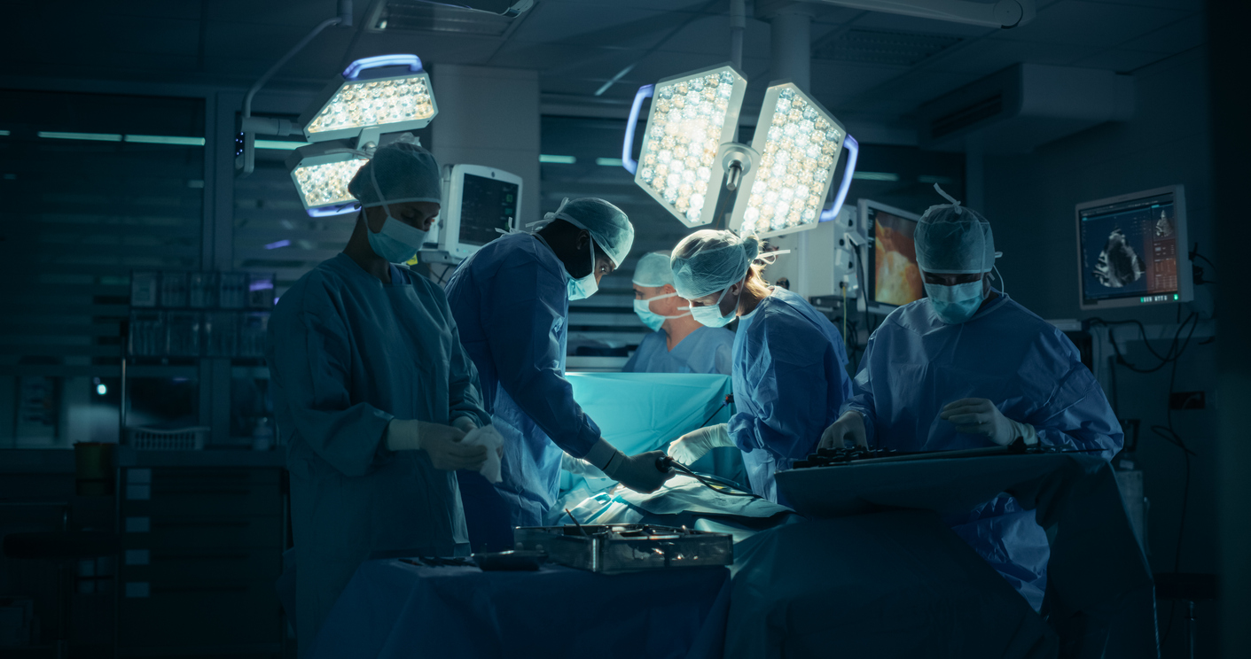 Surgical team performing operation in modern operating room with bright overhead lights