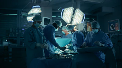 Surgical team performing operation in modern operating room with bright overhead lights