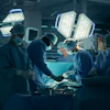 Surgical team performing operation in modern operating room with bright overhead lights