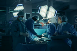 Surgical team performing operation in modern operating room with bright overhead lights