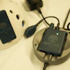 Two black Restore portable power banks with tree logo displayed on cream-colored charging dock with blue and black cables